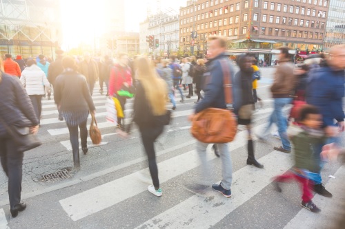 Uskarpt bilde av en mengde mennesker som går på sebraovergang i København sent på ettermiddagen. Noen av dem har også med seg sykkel, typisk transportmiddel i byen.